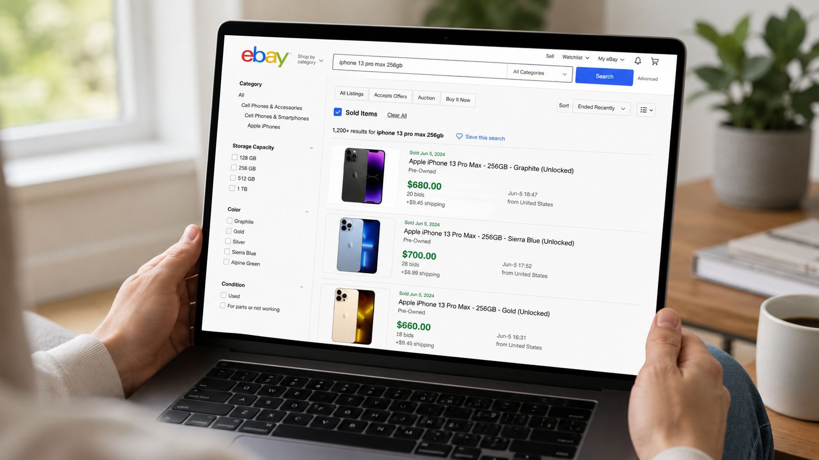 Person browsing completed iPhone 13 Pro Max listings on eBay via a laptop screen for price research.